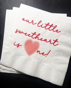 two white napkins with red lettering on them that say, our little sweetheart is me