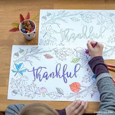 a young child is writing on a paper that says, thank you with leaves and acorns