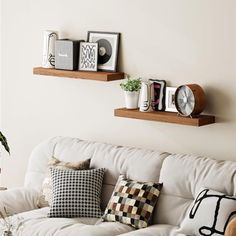 a living room with white couches and two wooden shelves on the wall above them