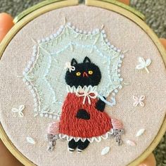 a hand embroidered picture of a black cat in a red dress