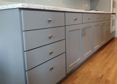 a kitchen with gray cabinets and white counter tops