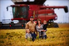 a man, woman and two children standing in front of a red combine