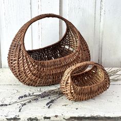 two wicker baskets sitting next to each other on a white table with dried lavender