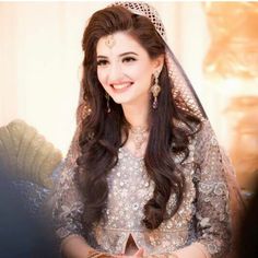 a woman in a bridal gown smiling for the camera with her hands clasped on her chest