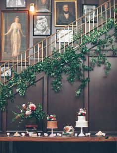 a table with cake and flowers on it in front of some framed pictures hanging on the wall