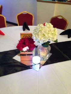 a vase with flowers on top of a table next to some shoes and boxes sitting on the floor