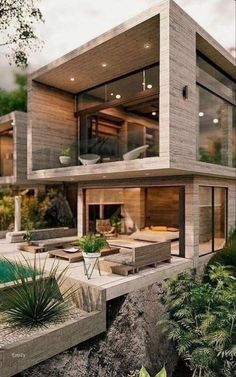 a modern house on the edge of a cliff overlooking a pool and lush greenery