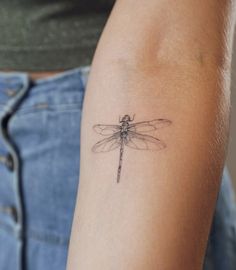 a small dragonfly tattoo on the arm