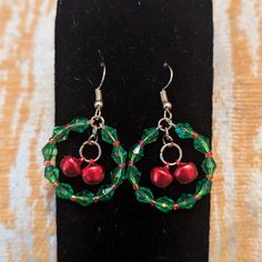 a pair of green and red beaded earrings with cherries on the hoops