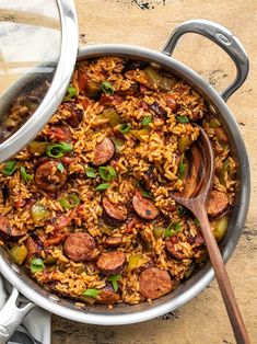 sausage and rice skillet in a pan with a wooden spoon next to it on a table