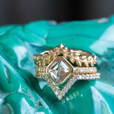 a close up view of two rings on top of a green leafy surface with diamonds