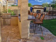 an outdoor kitchen and grill area with chairs