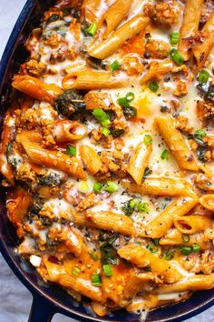 a skillet filled with pasta and meat covered in cheese