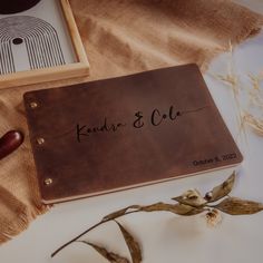 a wedding guest book with the name and date on it next to some dried flowers