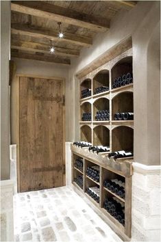 a wine cellar in the middle of a room with wooden shelves and bottles on it