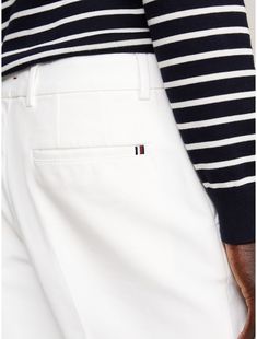 Tommy Hilfiger men's pant. These stretch-cotton chinos feature pressed creases and just a hint of branding for cool, casual styling.  Material: 97% Better Cotton Initiative, 3% Elastane. White Tapered Leg Chinos For Business Casual, White Straight Leg Chinos For Business Casual, White Tapered Leg Chinos For Work, Classic Tommy Hilfiger Tapered Leg Bottoms, Tommy Hilfiger Classic Tapered Leg Pants, White Cotton Chinos With Welt Pockets, Classic White Chinos With Pockets, White Cotton Tommy Hilfiger Bottoms, Classic Cotton Chinos With Pressed Crease