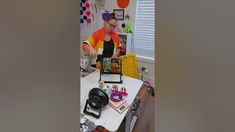 a woman in an orange shirt is making crafts at a table with other items on it