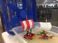 two legos are sitting on a table with a toy boat in front of them