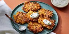 four crab cakes with sour cream on a plate next to a cup of yogurt