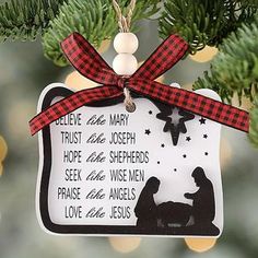 a christmas ornament hanging from a tree decorated with plaid ribbon and black silhouettes