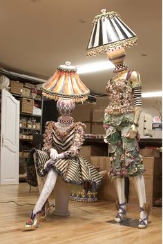 two mannequins are sitting next to each other in front of a lamp