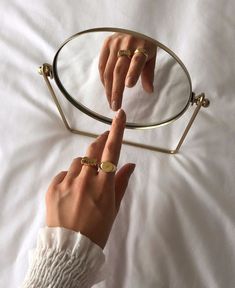 a woman's hand pointing at a pair of glasses on top of a bed