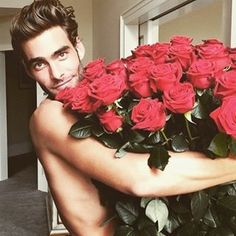 a man holding a large bouquet of red roses