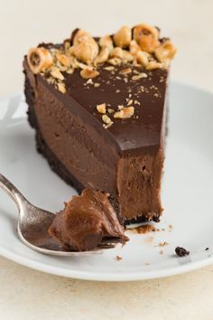 a slice of chocolate cheesecake on a white plate with a fork and text overlay reads no - bake nutella cheesecake