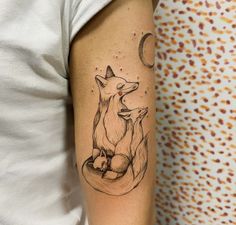 a woman's arm with a tattoo of two foxes sitting on top of each other