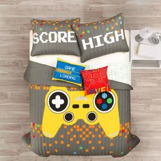 a bed with a video game controller comforter and pillows on top of the bed