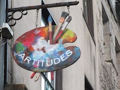 a sign hanging from the side of a building that says arttude's