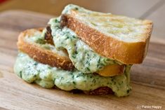 two pieces of bread are stacked on top of each other with pesto and cheese