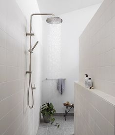 a shower head in the middle of a bathroom with white tiles on the walls and floor