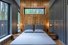 a bed sitting under a window in a bedroom next to a wooden wall and floor