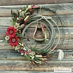 a wreath made out of rope with flowers and feathers hanging on the side of a wooden wall