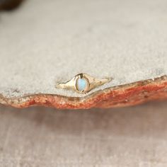 A small oval opal ring is set with prongs on an organically crafted 14k gold band. Yellow Gold Moonstone Ring With Ethiopian Opal, Fine Jewelry Gold Opal Birthstone Ring, Oval Gold Opal Ring In 14k Gold, Fine Jewelry 14k Gold Cabochon Moonstone Ring, 14k Gold Fine Jewelry Moonstone Cabochon Ring, 14k Gold Cabochon Moonstone Ring, Gold Opal Ring With Birthstone, 14k Gold Opal Ring With Polished Finish For Promise, Gold Opal Birthstone Ring