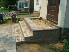 an outdoor patio with brick steps leading up to the front door and back yard area