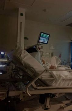 a hospital room with a monitor and medical equipment in the foreground, and two monitors on either side of the bed