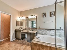 a bathroom with a large tub, sink and mirror in it's center area