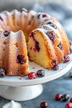 a bundt cake with cranberries and powdered sugar on the top is ready to be eaten