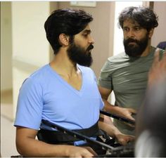 two men standing next to each other in front of a mirror with one man wearing a blue shirt