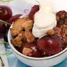 a white bowl filled with fruit and ice cream on top of a blue table cloth