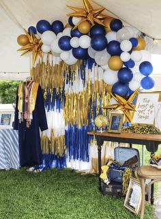 a party tent with balloons and streamers on the grass, stars hanging from the ceiling