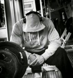 black and white photograph of a man wearing headphones sitting on a bench with luggage