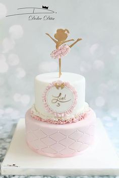 a pink and white cake with a ballerina on top