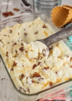 a scoop of ice cream in a glass dish with a metal spoon next to it