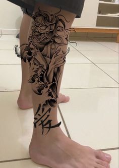 a person with a tattoo on their leg and legs is standing in front of a tile floor