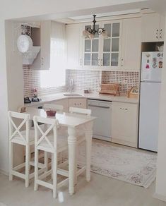 a kitchen with white cabinets and counter tops next to a table in the middle of the room