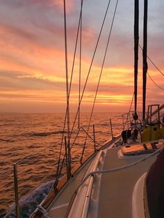 the sun is setting over the ocean on a sailboat