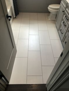 a bathroom with a toilet, sink and cabinets in it's center area is seen from the doorway